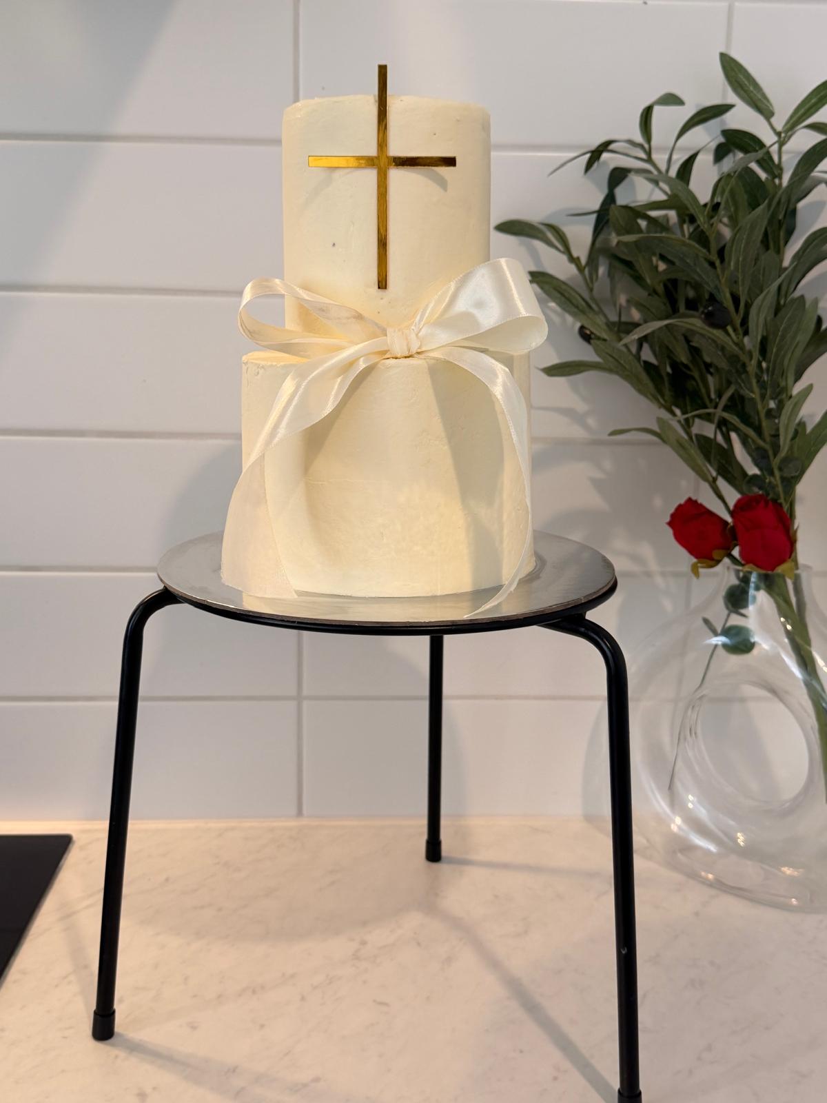 White christening cake with gold cross topper